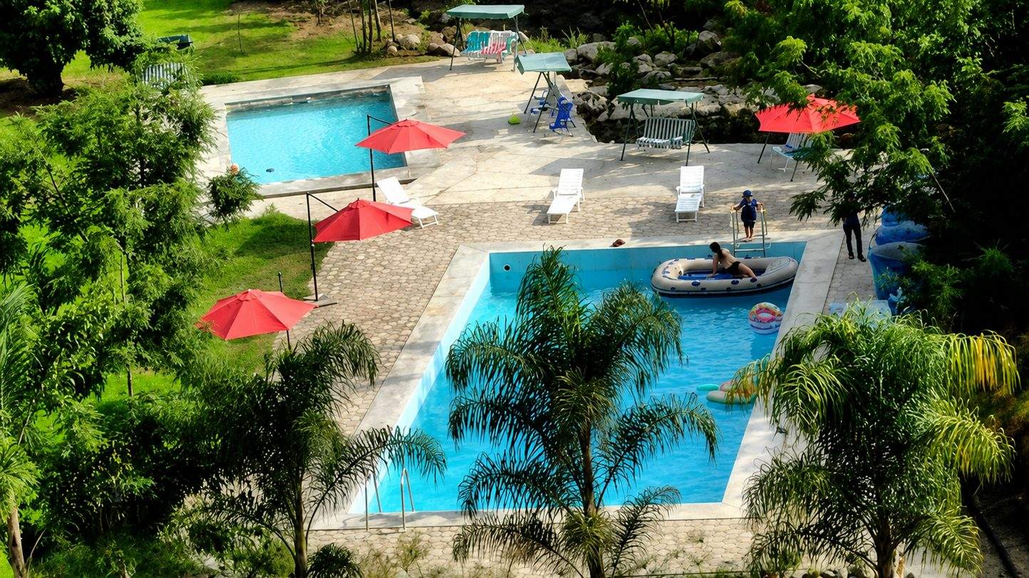 Vista aérea de las piscinas de Alpina Eco Lodge rodeadas de palmeras y montañas