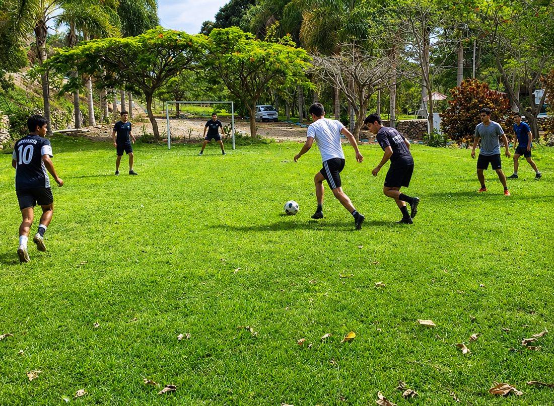 Grupo de amigos jugando fútbol en la cancha de Alpina