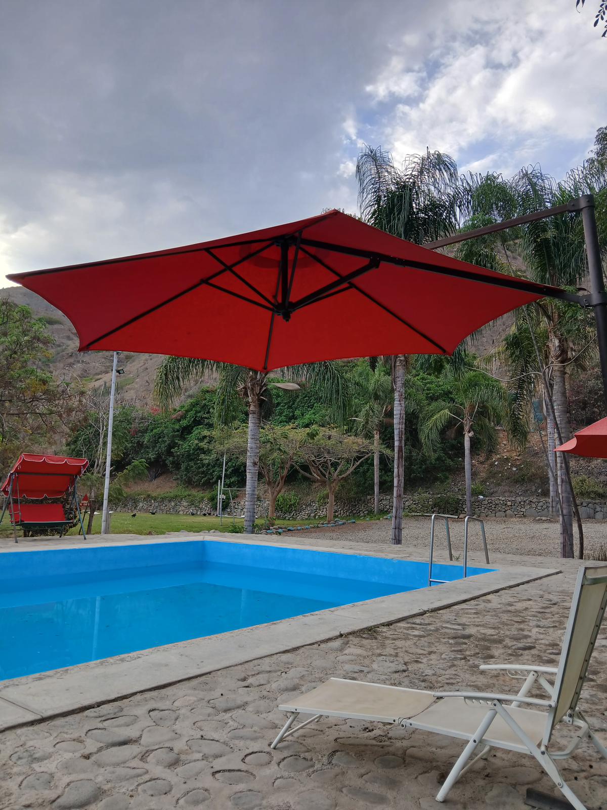 Sombrilla roja junto a la piscina